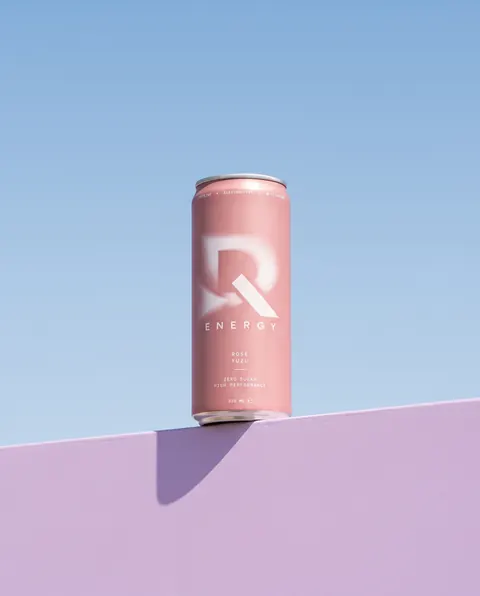 Dose DQ Energy Rose Yuzu auf einer fliederfarbenen Mauer vor Himmel
